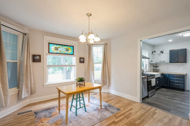 140 N 7th St, Carlisle, IA 50047 - dining space with wood finished floors, a chandelier, and baseboards