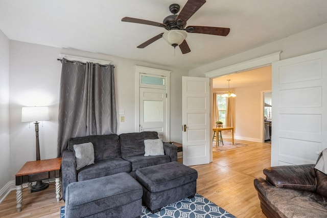 140 N 7th St, Carlisle, IA 50047 - living room featuring light wood-style flooring, a ceiling fan, baseboards, and a chandelier