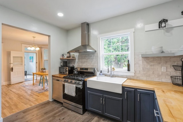 140 N 7th St, Carlisle, IA 50047 - kitchen with butcher block counters, wall chimney range hood, stainless steel gas range oven, a sink, and recessed lighting