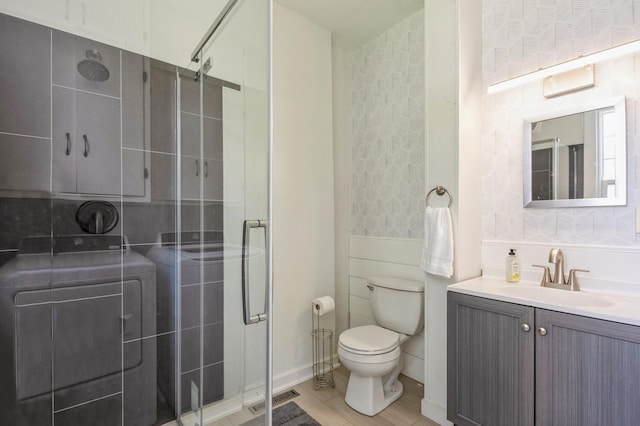 140 N 7th St, Carlisle, IA 50047 - bathroom featuring vanity, toilet, a shower stall, wallpapered walls, and washer / dryer
