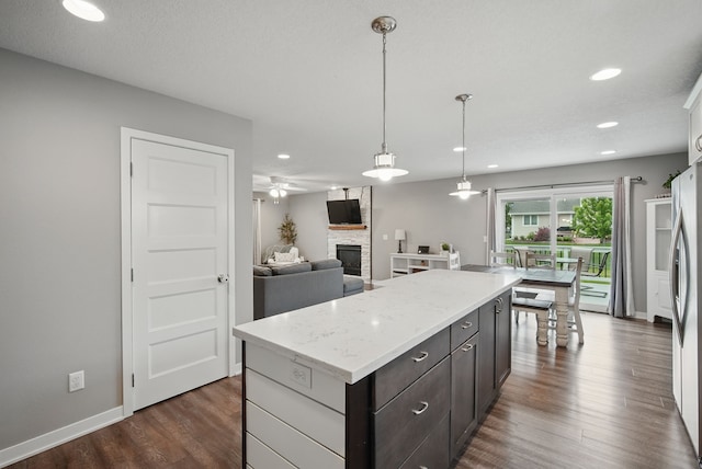 603 Elm Ct, Dallas Center, IA 50063 - kitchen featuring a stone fireplace, dark wood finished floors, recessed lighting, a ceiling fan, and a center island