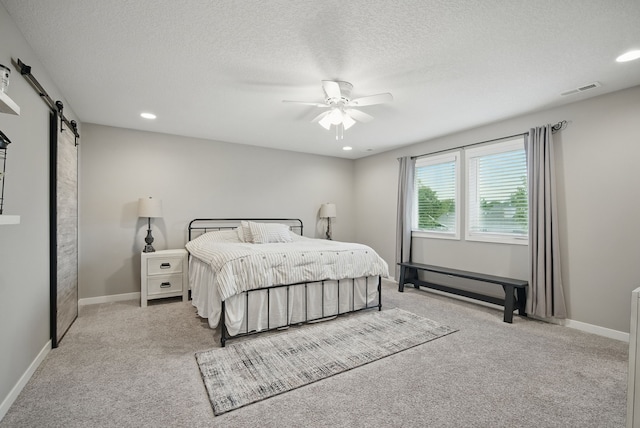 603 Elm Ct, Dallas Center, IA 50063 - bedroom with a barn door, light carpet, a textured ceiling, recessed lighting, and a ceiling fan