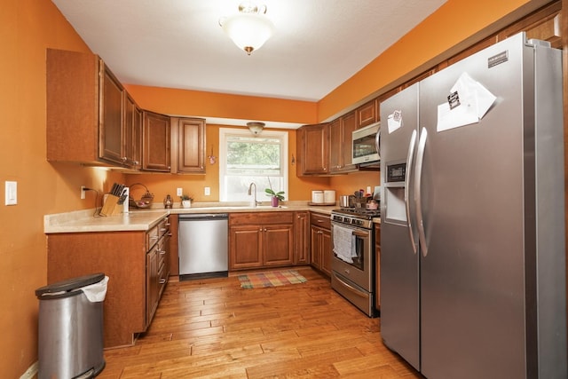 1617 Evergreen Ave, Des Moines, IA 50320 - kitchen with appliances with stainless steel finishes, light wood-style flooring, brown cabinets, light countertops, and a sink