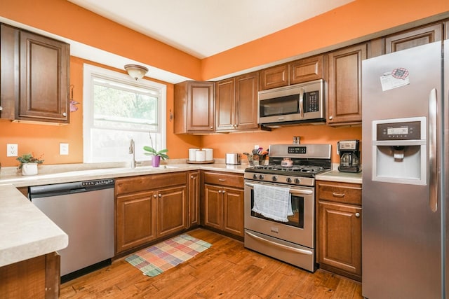1617 Evergreen Ave, Des Moines, IA 50320 - kitchen featuring appliances with stainless steel finishes, light wood-type flooring, light countertops, brown cabinets, and a sink