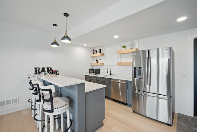 2216 Timberview Dr, Norwalk, IA 50211 - kitchen featuring stainless steel appliances, open shelves, a sink, a breakfast bar area, and light wood-type flooring