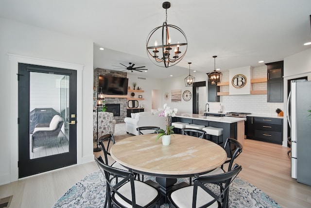 2216 Timberview Dr, Norwalk, IA 50211 - dining room with a glass covered fireplace, a chandelier, light wood-style flooring, ceiling fan, and recessed lighting