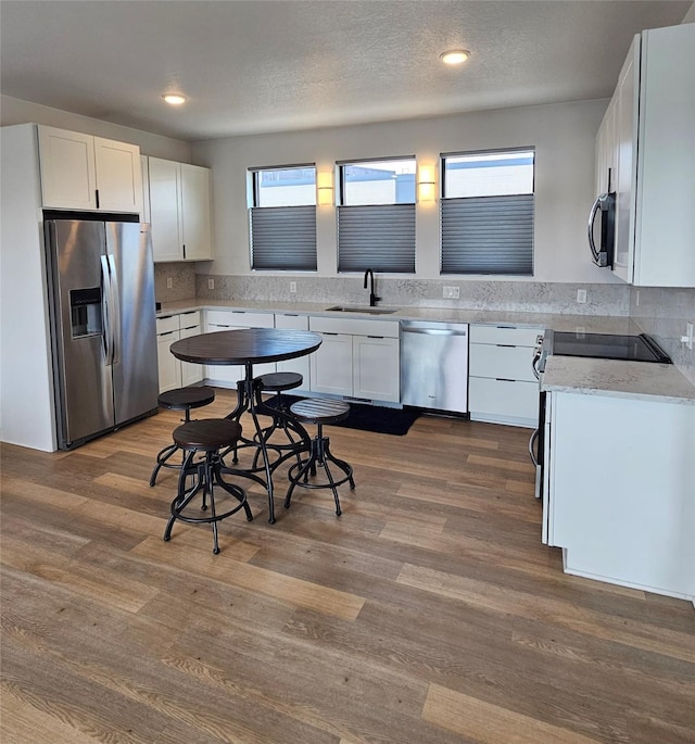 924 12th St, Des Moines, IA 50309 - kitchen featuring stainless steel appliances, a sink, white cabinets, dark wood-style flooring, and recessed lighting