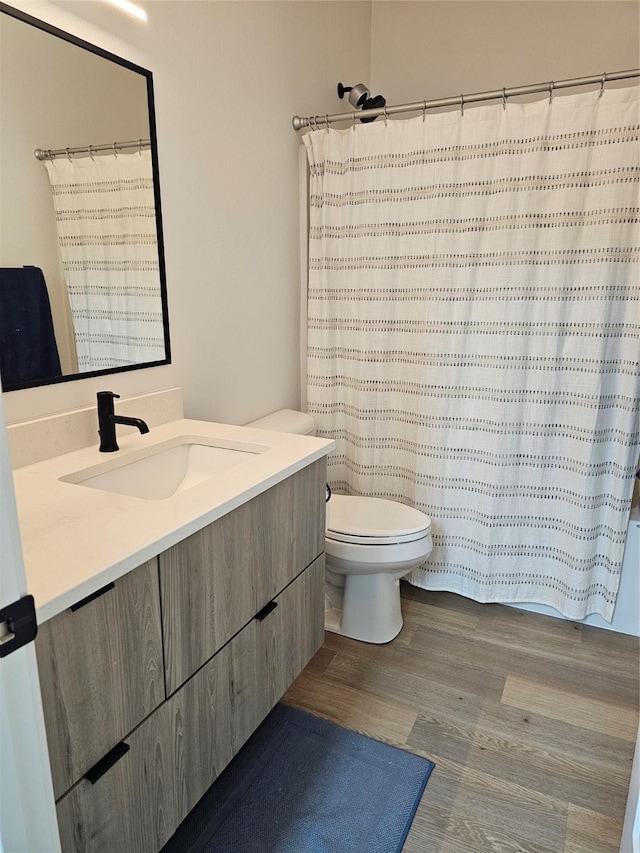 924 12th St, Des Moines, IA 50309 - bathroom featuring toilet, vanity, wood finished floors, and curtained shower