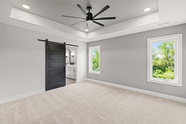 9814 Watermeadow Cir, Johnston, IA 50131 - unfurnished bedroom featuring a raised ceiling, a barn door, baseboards, light carpet, and recessed lighting