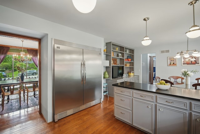 711 36th St, West Des Moines, IA 50265 - kitchen with built in fridge, a chandelier, dark countertops, and gray cabinetry