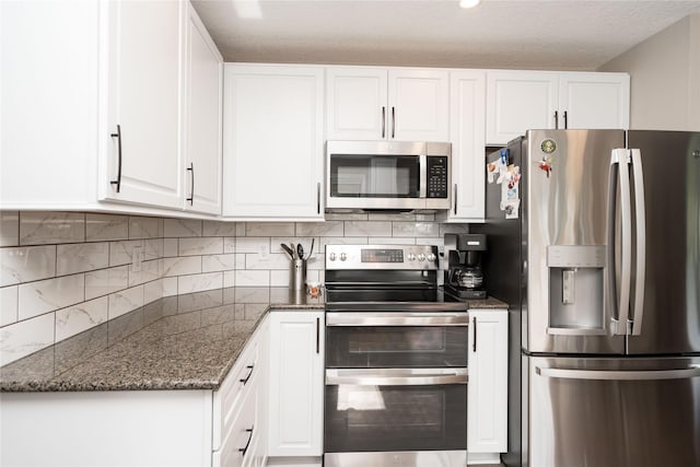 6640 Monticello Ct, Johnston, IA 50131 - kitchen featuring appliances with stainless steel finishes, white cabinets, dark stone countertops, and a textured ceiling