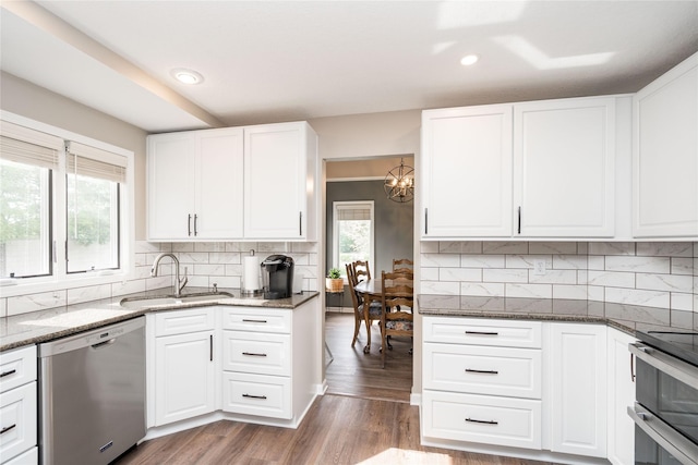 6640 Monticello Ct, Johnston, IA 50131 - kitchen with appliances with stainless steel finishes, a sink, dark stone countertops, wood finished floors, and recessed lighting