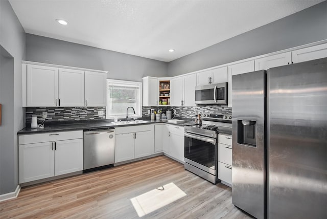 3421 Amherst St, Des Moines, IA 50313 - kitchen featuring appliances with stainless steel finishes, dark countertops, a sink, light wood-style flooring, and tasteful backsplash