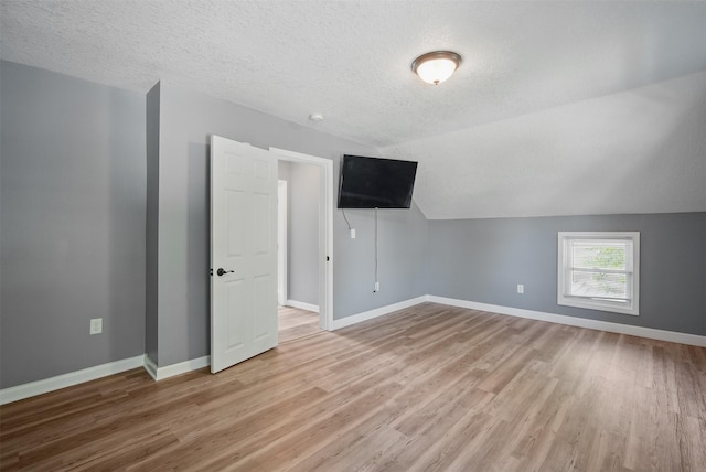 3421 Amherst St, Des Moines, IA 50313 - additional living space featuring light wood-style flooring, baseboards, lofted ceiling, and a textured ceiling