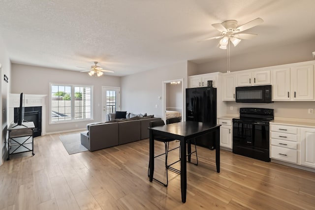 1335 SE Florence Dr Unit 312, Waukee, IA 50263 - kitchen featuring black appliances, ceiling fan, white cabinetry, open floor plan, and light countertops