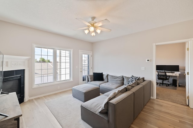 1335 SE Florence Dr Unit 312, Waukee, IA 50263 - living area featuring a ceiling fan, a desk, light wood-style flooring, a fireplace, and baseboards