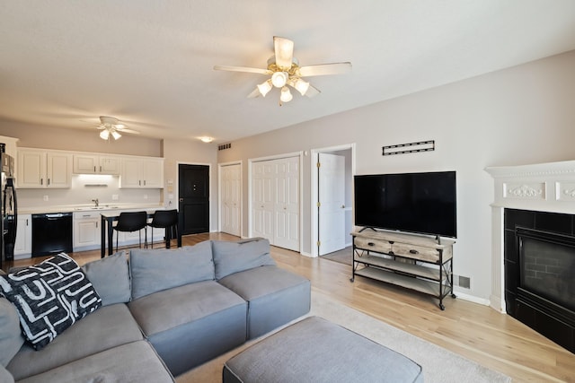 1335 SE Florence Dr Unit 312, Waukee, IA 50263 - living room featuring a ceiling fan, light wood-style floors, a fireplace, and baseboards