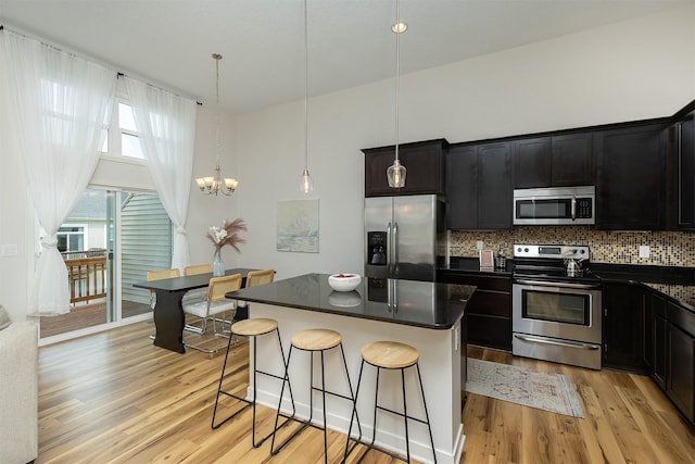 196 79th St, West Des Moines, IA 50266 - kitchen featuring appliances with stainless steel finishes, dark countertops, a breakfast bar area, a chandelier, and a kitchen island