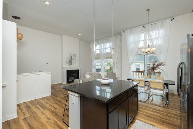 196 79th St, West Des Moines, IA 50266 - kitchen featuring refrigerator with ice dispenser, light wood finished floors, a fireplace, dark brown cabinetry, and recessed lighting