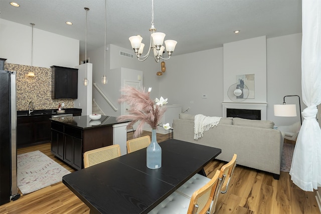 196 79th St, West Des Moines, IA 50266 - dining area featuring a chandelier, light wood-style floors, recessed lighting, a fireplace, and stairway