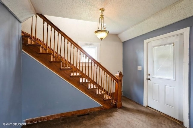 2638 Capitol Ave, Des Moines, IA 50317 - foyer featuring carpet flooring, vaulted ceiling, stairs, and a textured ceiling