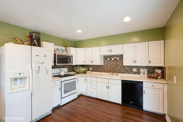2638 Capitol Ave, Des Moines, IA 50317 - kitchen featuring white appliances, a sink, dark wood-type flooring, decorative backsplash, and white cabinetry