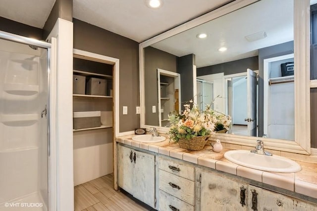 2638 Capitol Ave, Des Moines, IA 50317 - bathroom featuring a stall shower, double vanity, recessed lighting, and wood finished floors