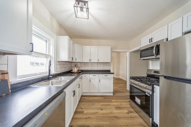 212 Nile Kinnick Dr N, Adel, IA 50003 - kitchen with stainless steel appliances, a sink, light wood-style floors, white cabinets, and dark countertops
