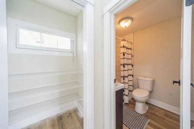 212 Nile Kinnick Dr N, Adel, IA 50003 - bathroom featuring toilet, wood finished floors, a shower with curtain, and baseboards