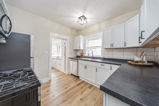 212 Nile Kinnick Dr N, Adel, IA 50003 - kitchen with a sink, appliances with stainless steel finishes, dark countertops, decorative backsplash, and light wood finished floors