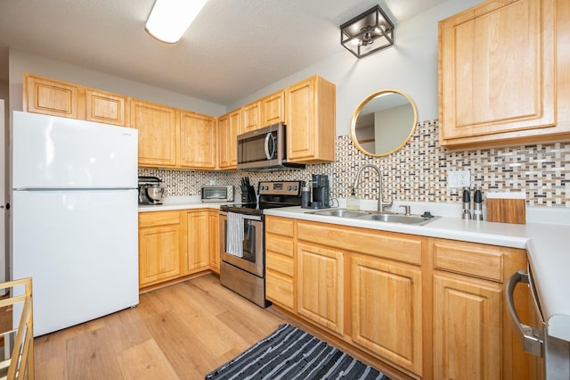 5221 Village Run Ave Unit 402, Des Moines, IA 50317 - kitchen with appliances with stainless steel finishes, a sink, light brown cabinets, light wood-type flooring, and light countertops