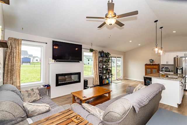 513 Walnut Dr, Huxley, IA 50124 - living area with lofted ceiling, light wood-style floors, a glass covered fireplace, a ceiling fan, and recessed lighting