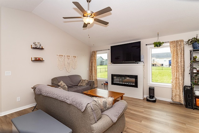 513 Walnut Dr, Huxley, IA 50124 - living area with vaulted ceiling, light wood-type flooring, ceiling fan, a glass covered fireplace, and baseboards