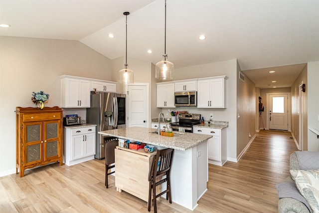 513 Walnut Dr, Huxley, IA 50124 - kitchen featuring stainless steel appliances, light wood finished floors, a breakfast bar, white cabinets, and vaulted ceiling