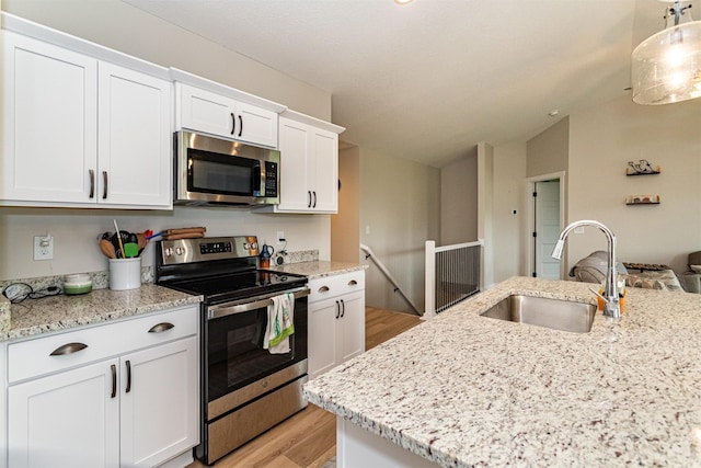513 Walnut Dr, Huxley, IA 50124 - kitchen with appliances with stainless steel finishes, a sink, light wood finished floors, lofted ceiling, and white cabinets