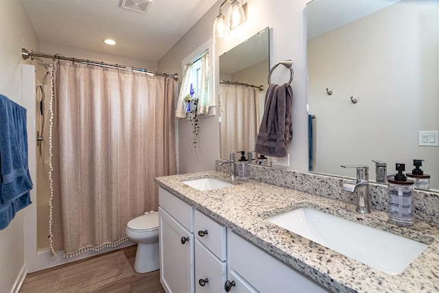 513 Walnut Dr, Huxley, IA 50124 - full bathroom featuring toilet, double vanity, wood finished floors, shower / bath combo, and recessed lighting