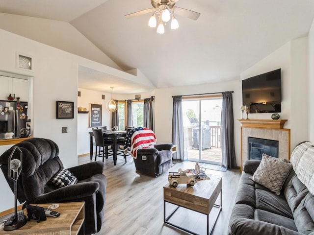 5213 SE 30th St, Des Moines, IA 50320 - living area with vaulted ceiling, light wood finished floors, a ceiling fan, a tile fireplace, and baseboards