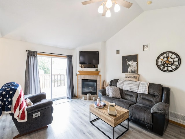 5213 SE 30th St, Des Moines, IA 50320 - living room with wood finished floors, a ceiling fan, a tiled fireplace, and high vaulted ceiling