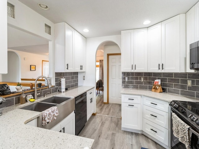 5213 SE 30th St, Des Moines, IA 50320 - kitchen with dishwashing machine, a sink, arched walkways, black range, and light stone counters