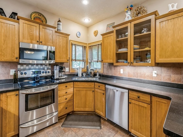 6818 Jules Verne Ct, Johnston, IA 50131 - kitchen featuring stainless steel appliances, a sink, glass insert cabinets, backsplash, and dark countertops