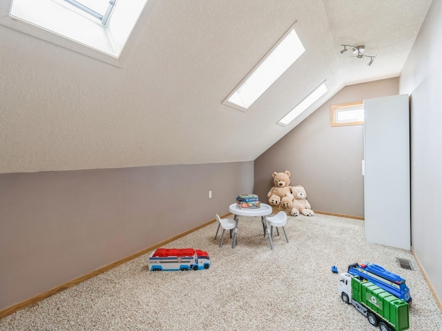 6818 Jules Verne Ct, Johnston, IA 50131 - recreation room with a skylight, vaulted ceiling, carpet, baseboards, and a textured ceiling
