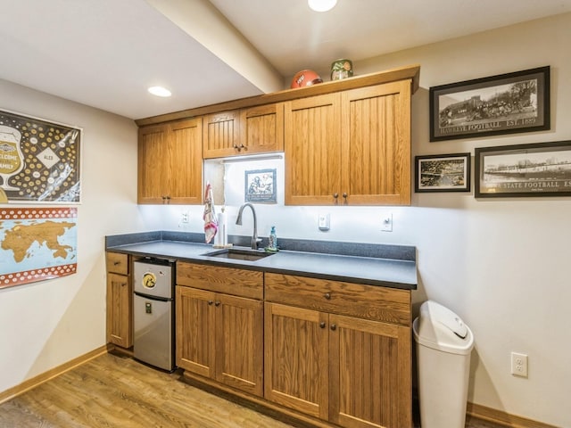 6818 Jules Verne Ct, Johnston, IA 50131 - kitchen with dark countertops, a sink, light wood-type flooring, baseboards, and brown cabinetry