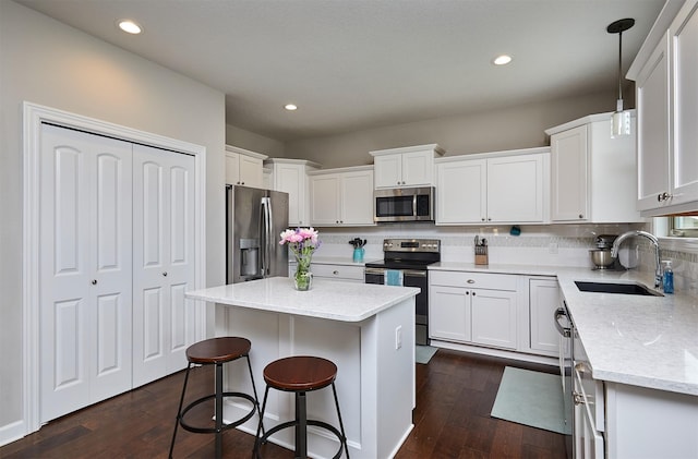1880 Brodie St, Waukee, IA 50263 - kitchen with stainless steel appliances, a sink, a kitchen island, dark wood finished floors, and white cabinets