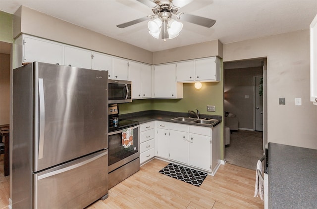 4006 67th St, Urbandale, IA 50322 - kitchen featuring stainless steel appliances, a sink, a ceiling fan, light wood-style floors, and dark countertops
