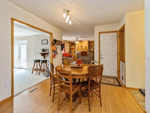 1506 W 17th St S, Newton, IA 50208 - dining room featuring light wood finished floors, a ceiling fan, a textured ceiling, and baseboards