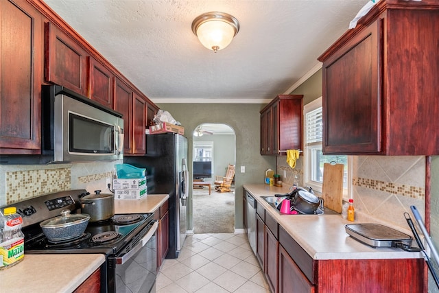 1452 55th St, Des Moines, IA 50311 - kitchen featuring stainless steel appliances, reddish brown cabinets, light countertops, arched walkways, and ornamental molding