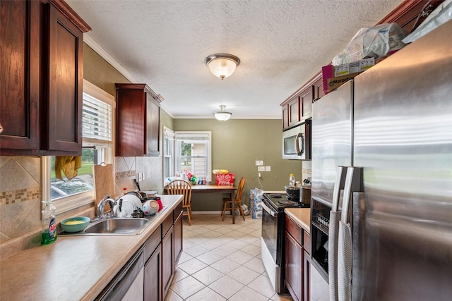 1452 55th St, Des Moines, IA 50311 - kitchen featuring stainless steel appliances, a sink, tasteful backsplash, ornamental molding, and light tile patterned floors