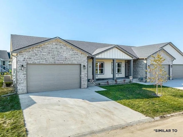 277 S Marigold Ave, West Des Moines, IA 50266 - view of front of home featuring an attached garage, driveway, a front yard, stone siding, and board and batten siding