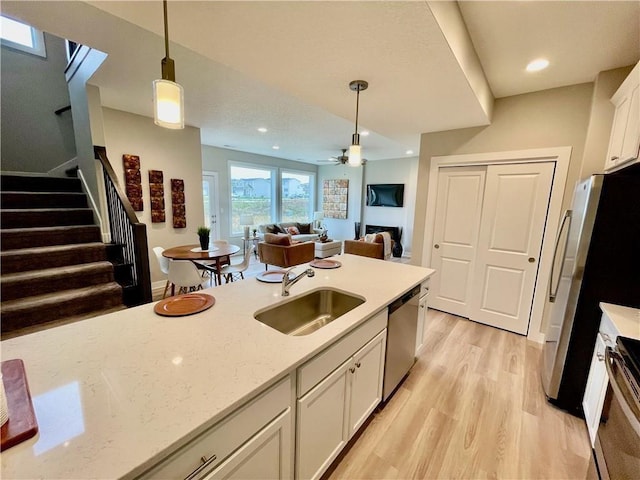 5426 153rd St, Urbandale, IA 50323 - kitchen with a sink, appliances with stainless steel finishes, light wood-type flooring, white cabinetry, and pendant lighting