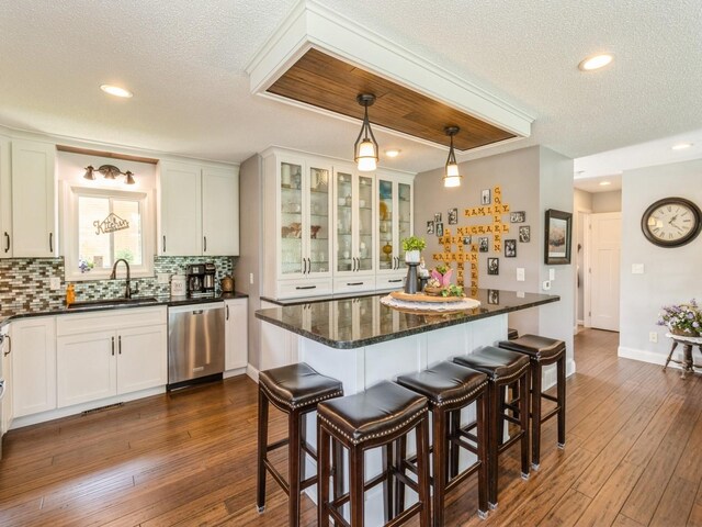 201 Cottage Ln, Montezuma, IA 50171 - kitchen with stainless steel dishwasher, a textured ceiling, backsplash, a sink, and white cabinets